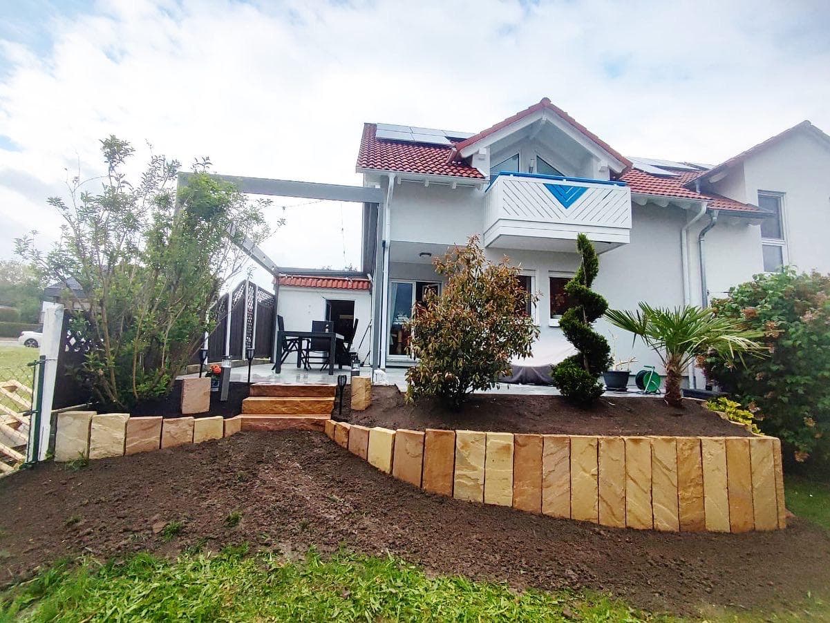 Garten mit neuer Sandstein-Stützmauer und frischer Bepflanzung