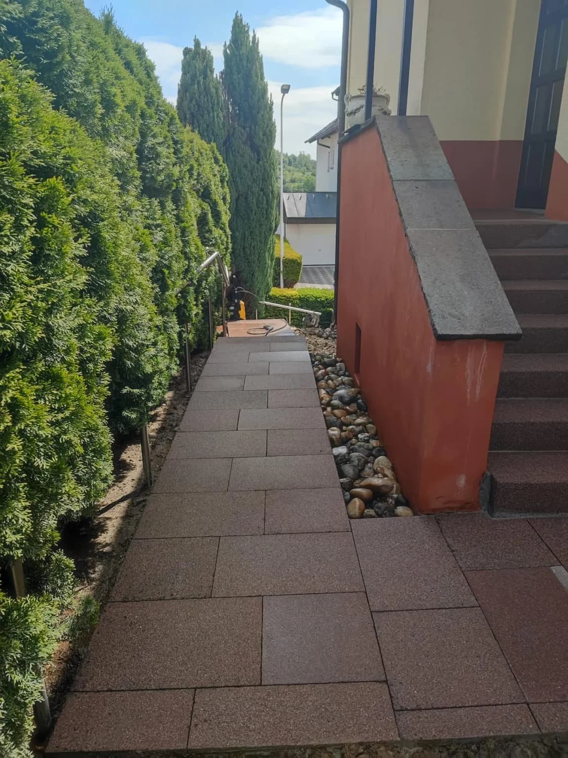 Neu gepflasterter Zugangsweg entlang der Hecke nach Abschluss der Sanierung