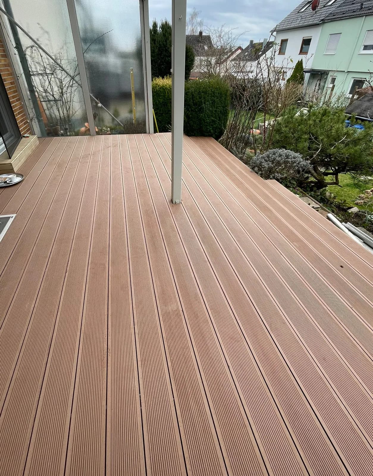 WPC-Terrasse mit angrenzendem, gepflegtem Garten an einem Wohnhaus